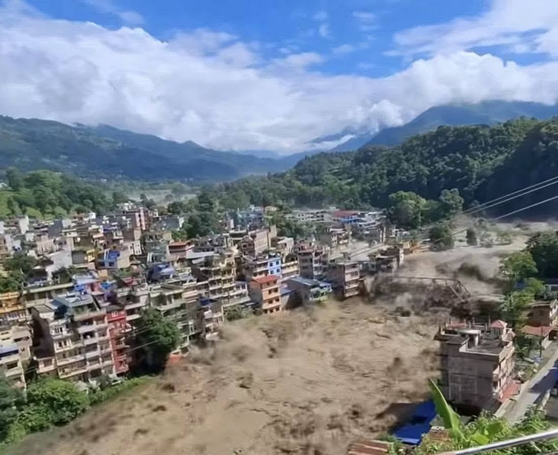 A hillside town beside the raging brown river during the flood