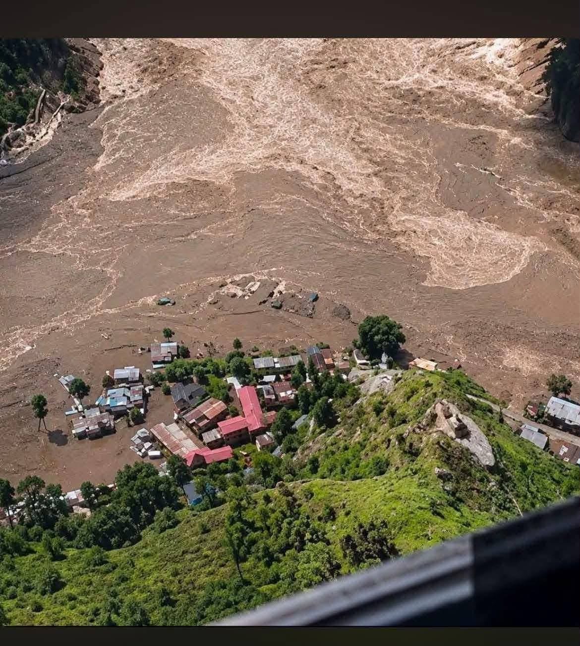Aerial view of a village stranded on a ridge above the flooded river